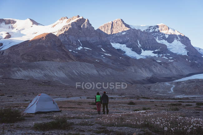 Вид сзади на пару, смотрящую на горы в снежных шапках — стоковое фото