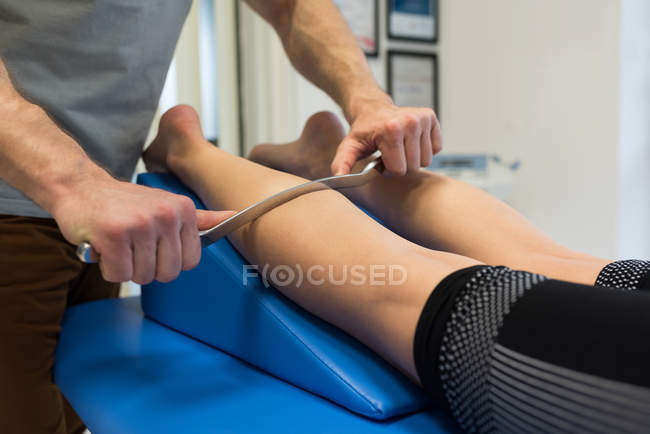 Physiotherapist giving leg massage to woman in clinic — Stock Photo
