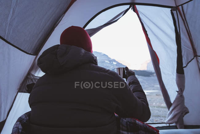 Rear view of man having coffee in tent — Stock Photo