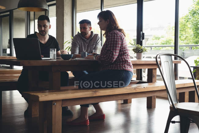 Коллеги по бизнесу работают над ноутбуком в кафетерии в офисе — стоковое фото