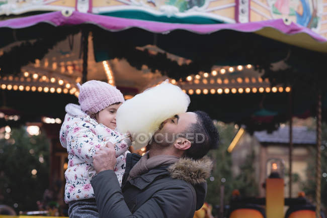 Батько і дочка, маючи бавовна цукерки в сутінках в Луна-парк — стокове фото