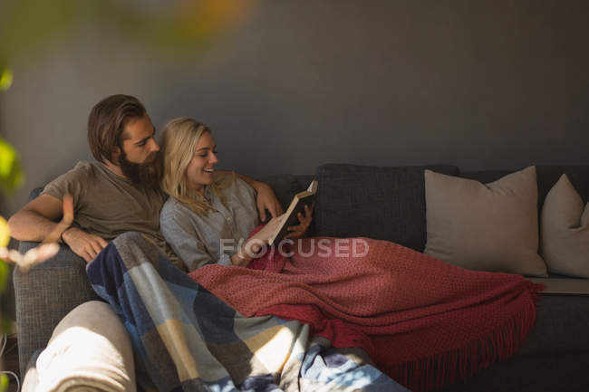 Paar liest zu Hause im Wohnzimmer ein Buch — Stockfoto
