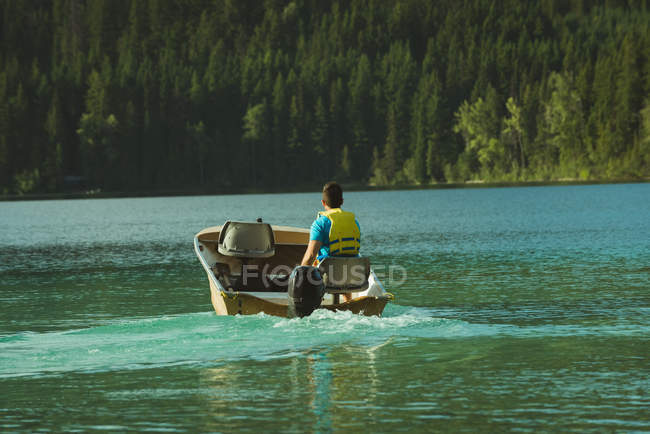 Вид сзади на человека, путешествующего на моторной лодке в озере — стоковое фото
