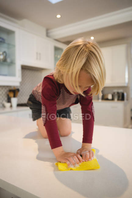 Menino limpeza cozinha bancada com pano em casa — Fotografia de Stock