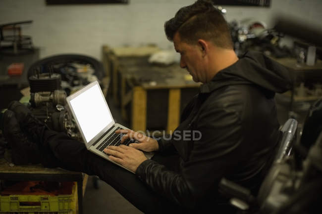 Side view of mechanic using laptop in garage — Stock Photo