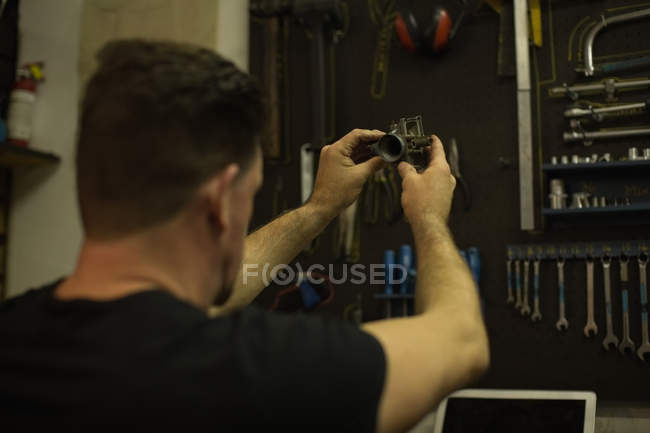 Mechaniker überprüft Motorradteile in Garage — Stockfoto