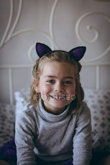 Портрет улыбающейся девушки, сидящей на кровати в спальне — стоковое фото