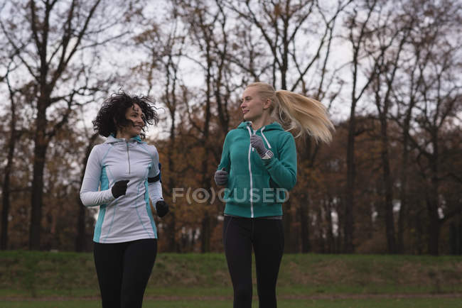Two young female friends jogging in the park — Stock Photo