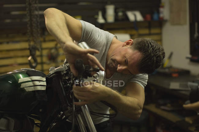 Mécanicien vérifiant les freins d'une moto dans le garage — Photo de stock