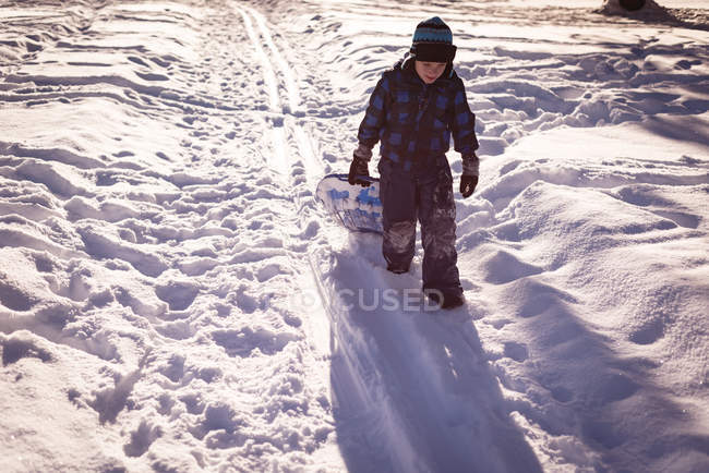 Chica caminando con trineo en la nieve durante el invierno - foto de stock