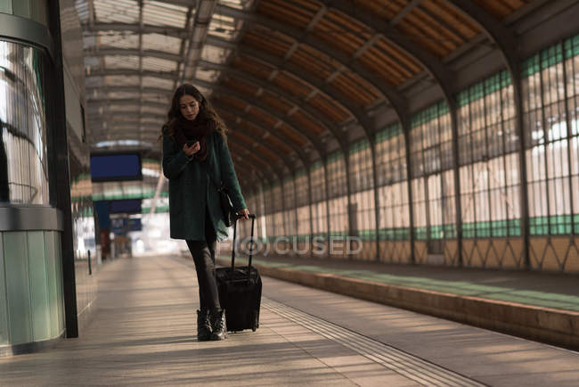 Женщина, использующая мобильный телефон на вокзале — стоковое фото