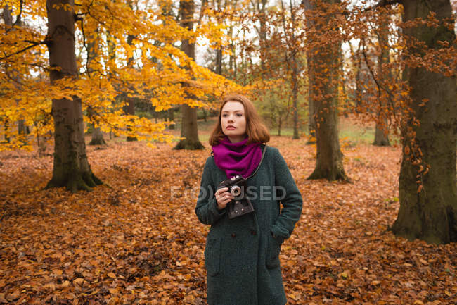Femme tenant caméra vintage dans le parc pendant l'automne — Photo de stock