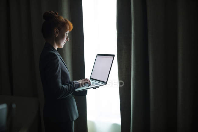 Femme d'affaires utilisant un ordinateur portable dans la chambre d'hôtel — Photo de stock