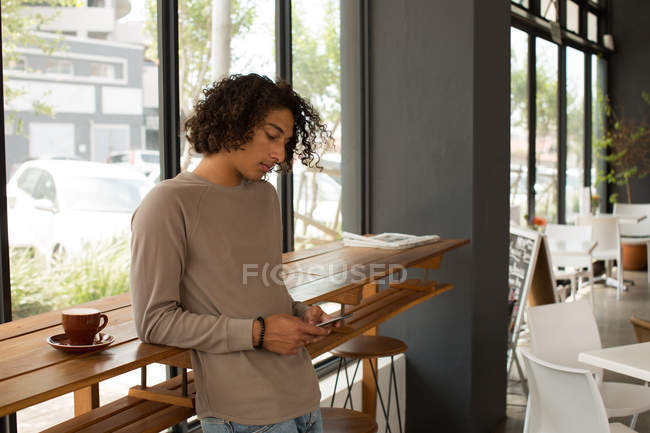 Junger Mann benutzt Handy in Restaurant — Stockfoto