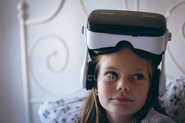 Menina com fone de ouvido realidade virtual sentado na cama em casa — Fotografia de Stock