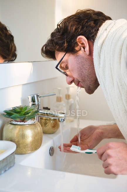 Homem limpando a boca com água no banheiro em casa — Fotografia de Stock