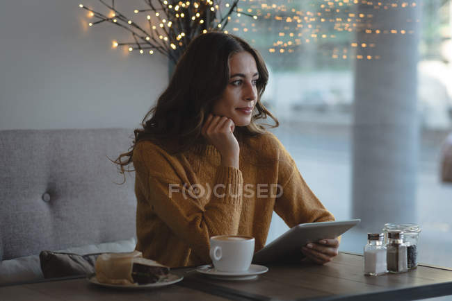 Mujer reflexiva usando tableta digital en el restaurante - foto de stock