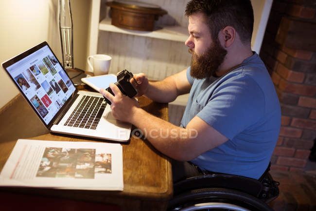 Людина з обмеженими можливостями дивиться фотографії в камері вдома — стокове фото
