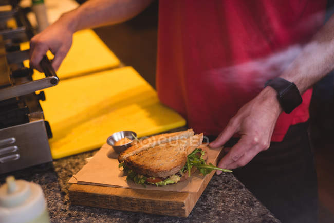 Close-up of male waiter preparing sandwich in cafe — Stock Photo