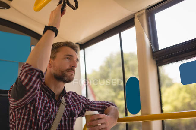 Hombre pensativo tomando una taza de café mientras viaja en tranvía - foto de stock