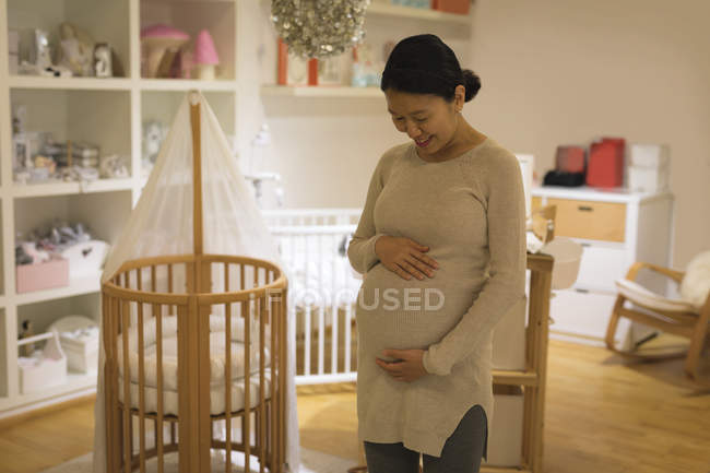Happy pregnant woman touching her belly in store — Stock Photo
