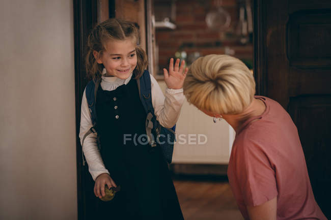 Hija feliz interactuando con la madre mientras va a la escuela - foto de stock