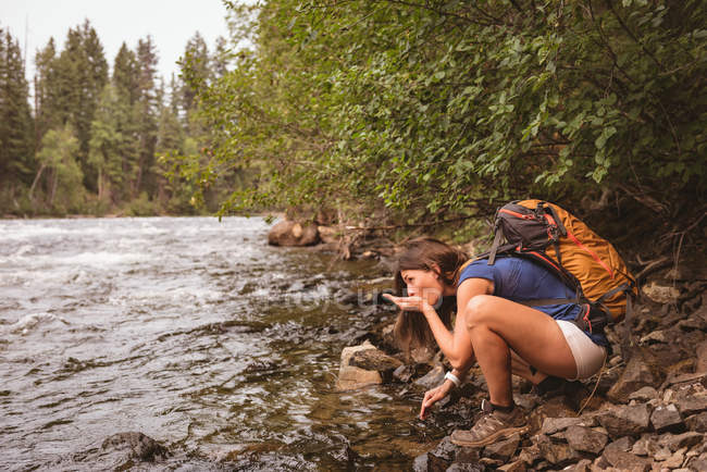 Vista laterale della donna che beve acqua dal fiume — Foto stock