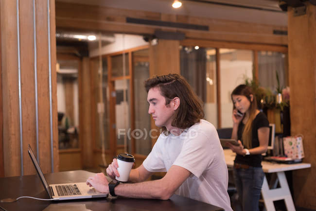 Joven ejecutivo utilizando el ordenador portátil en la oficina - foto de stock