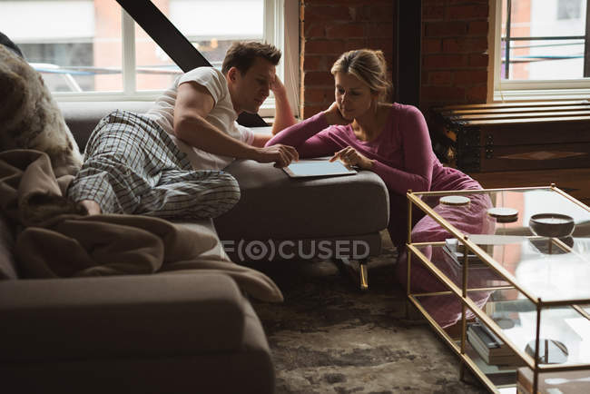 Пара с помощью цифрового планшета в гостиной на дому — стоковое фото