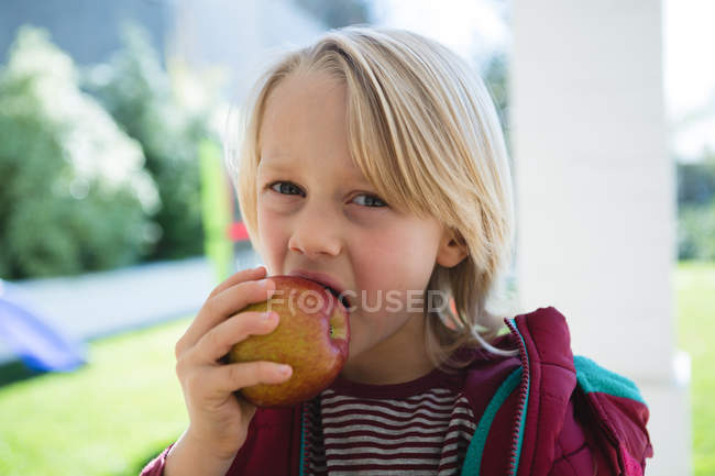 Niño comiendo manzana en el porche en casa - foto de stock