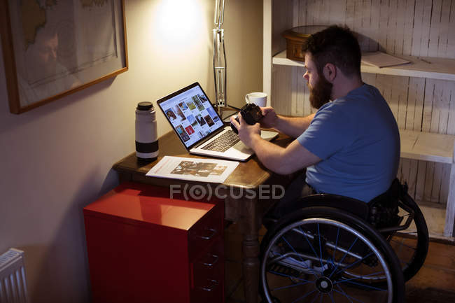 Homem com deficiência olhando para fotos na câmera em casa — Fotografia de Stock