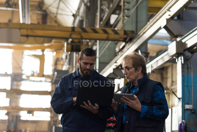Техники обсуждают за ноутбуком в металлургии — стоковое фото