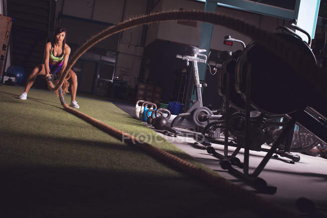 Fit mulher fazendo exercício de corda de batalha no ginásio — Fotografia de Stock