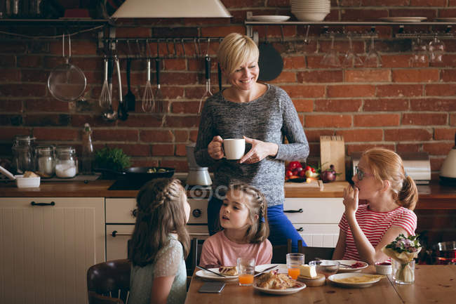 Mãe e filhos tomando café da manhã à mesa na cozinha — Fotografia de Stock