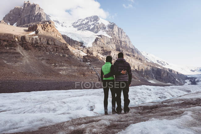 Couple debout avec bras autour de la montagne — Photo de stock