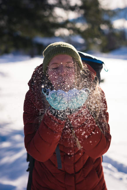 Bella donna che soffia neve dalle sue mani in inverno — Foto stock