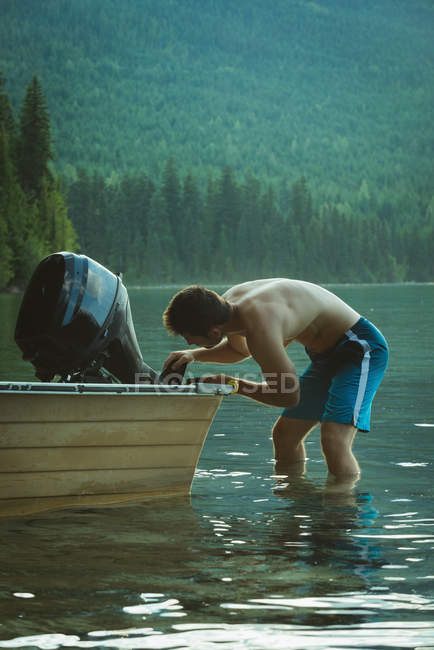 Homme réparant un moteur de bateau à moteur dans un lac — Photo de stock