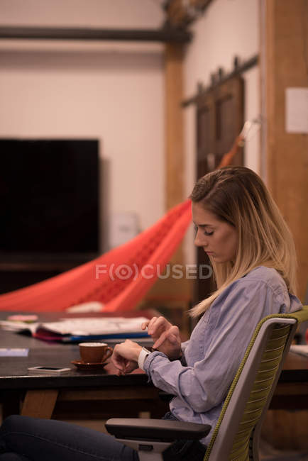 Femmina esecutivo utilizzando smartwatch in ufficio — Foto stock