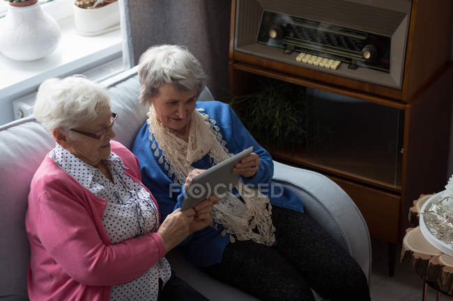 Старшие друзья используют цифровой планшет дома — стоковое фото
