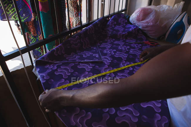 Tailor measuring a fabric in shop — Stock Photo