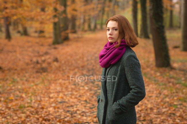 Frau steht im Herbst mit der Hand in der Tasche im Park — Stockfoto