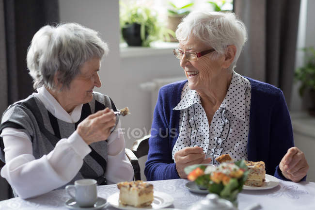 Amigos seniores interagindo bruxa uns aos outros enquanto toma café da manhã em casa — Fotografia de Stock