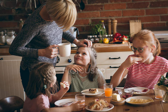 Mãe interagindo com a filha enquanto toma café da manhã na mesa — Fotografia de Stock