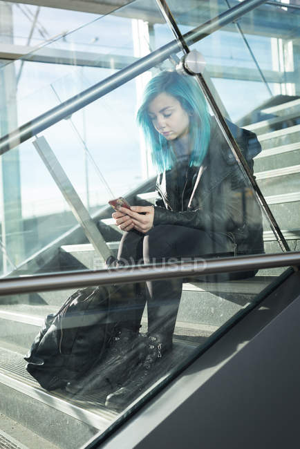 Stilvolle Frau benutzt Handy im Treppenhaus — Stockfoto