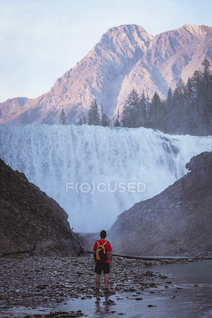 Вид сзади на человека, смотрящего на водопад — стоковое фото