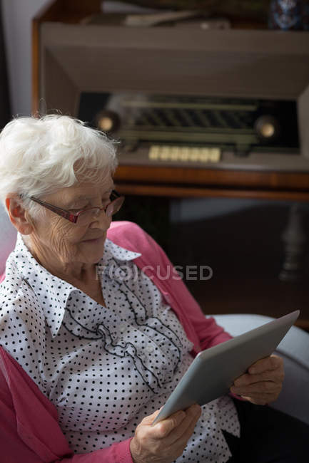 Donna anziana che utilizza tablet digitale a casa — Foto stock