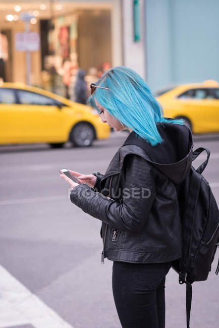 Mujer con estilo utilizando el teléfono móvil en la calle de la ciudad - foto de stock