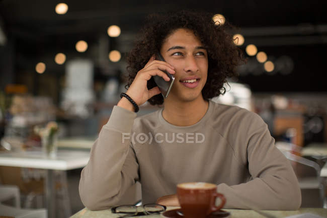 Young man talking on mobile phone in restaurant — Stock Photo