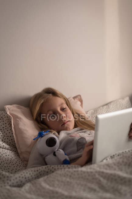 Girl using digital tablet in bedroom at home — Stock Photo