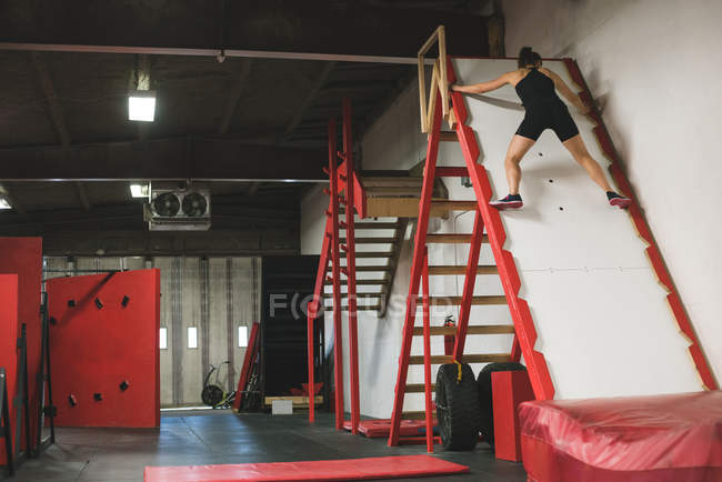 Muskulöse Frau klettert in der Turnhalle auf eine schiefe Rutsche — Stockfoto
